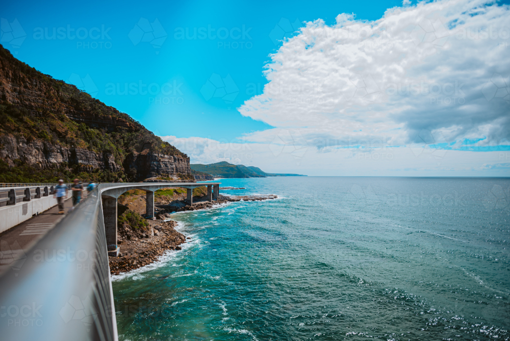 people walking on the sea cliff bridge overlooking the ocean - Australian Stock Image