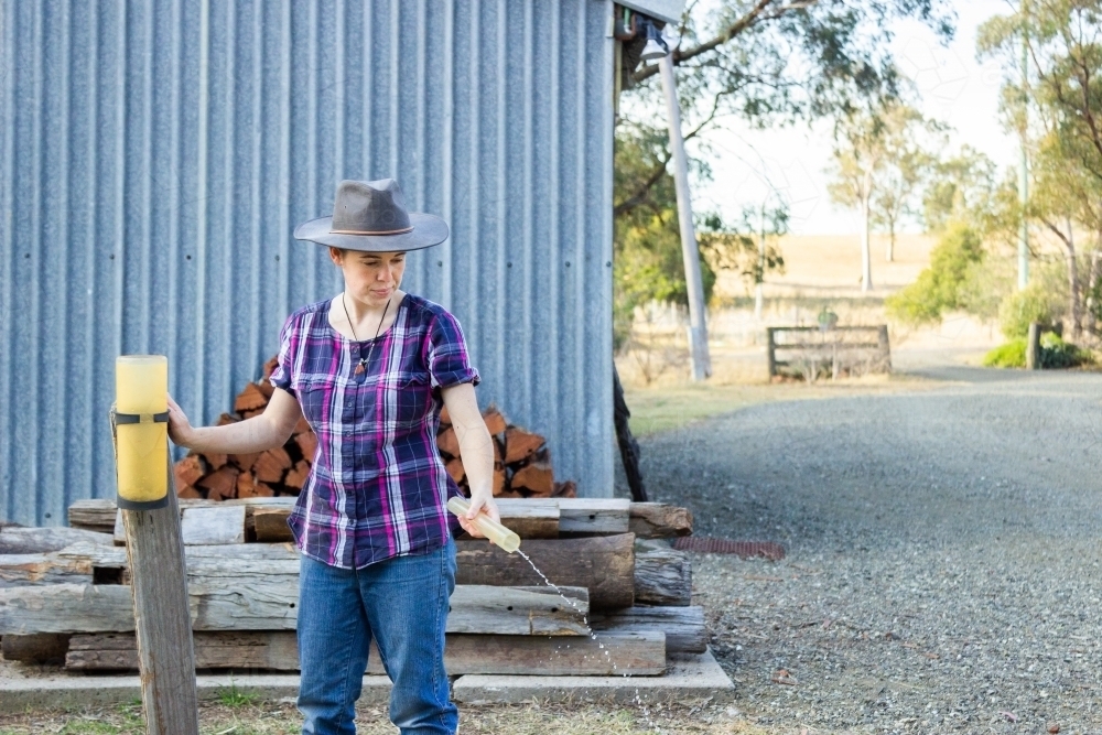 Person emptying out rain gauge after measuring rain - Australian Stock Image