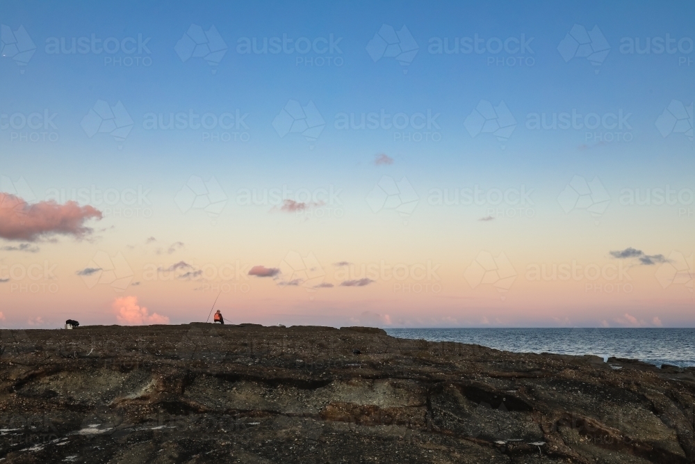 Person fishing from rocks at Norah Head, New South Wales Australia - Australian Stock Image