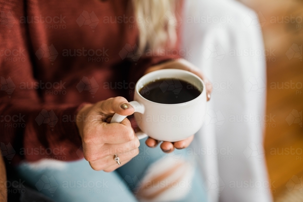 Person holding a cup of black coffee - Australian Stock Image