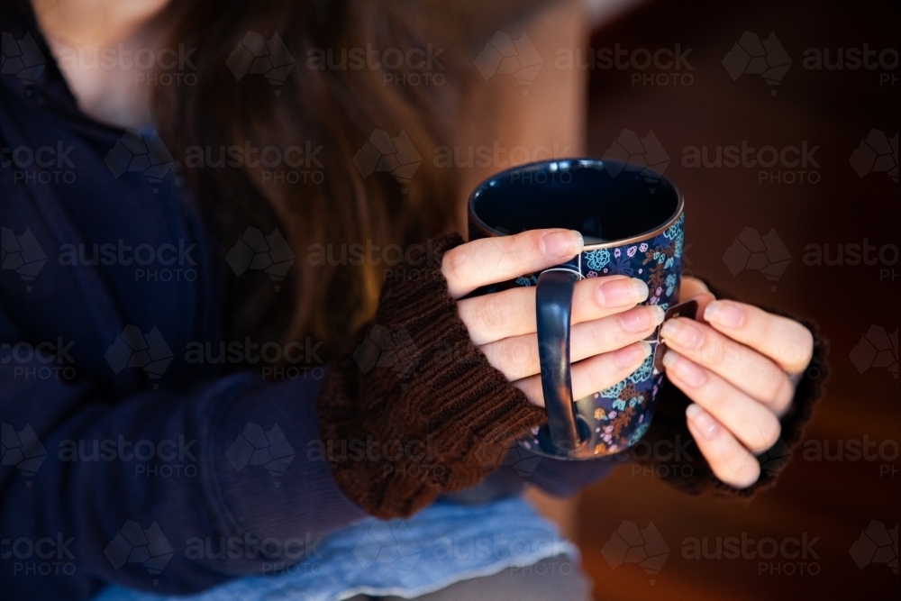 Person holding cup of chai tea in winter to keep warm - Australian Stock Image