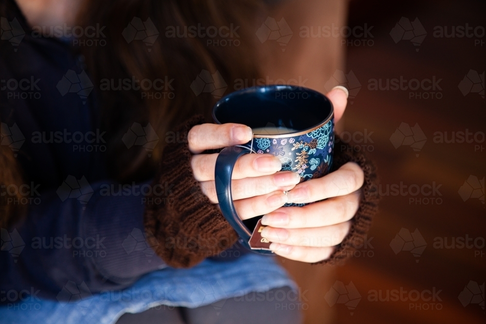 Person holding cup of chai tea in winter to keep warm - Australian Stock Image
