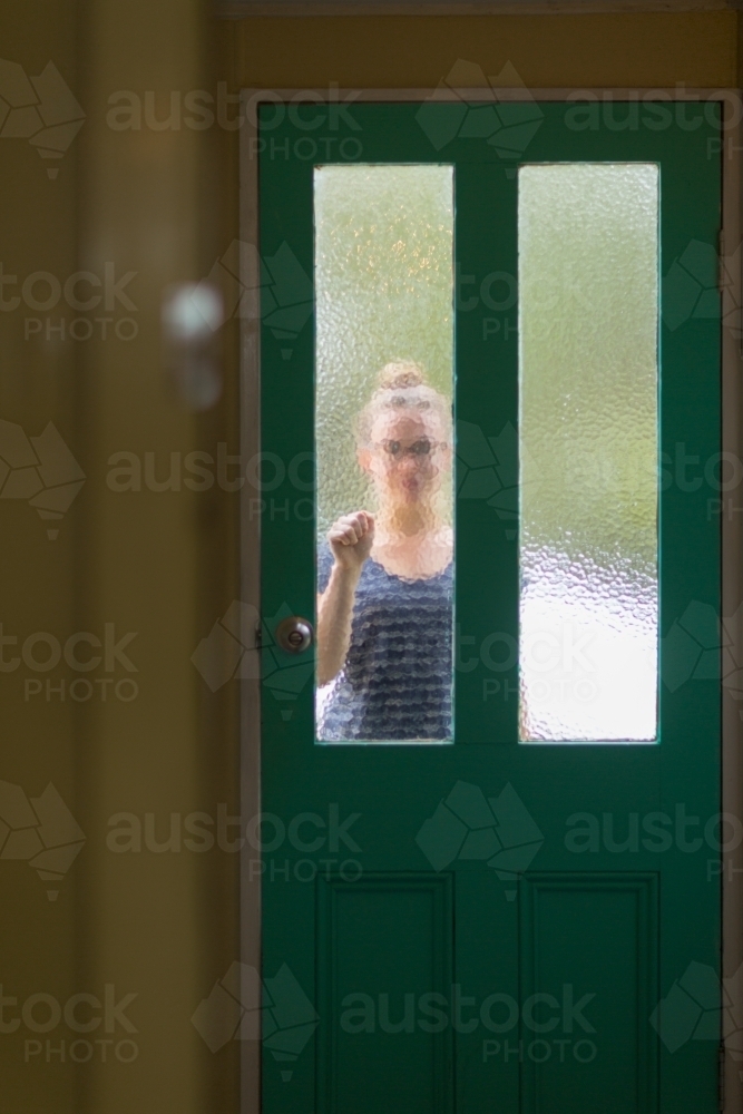 Person knocking on frosted glass door - Australian Stock Image