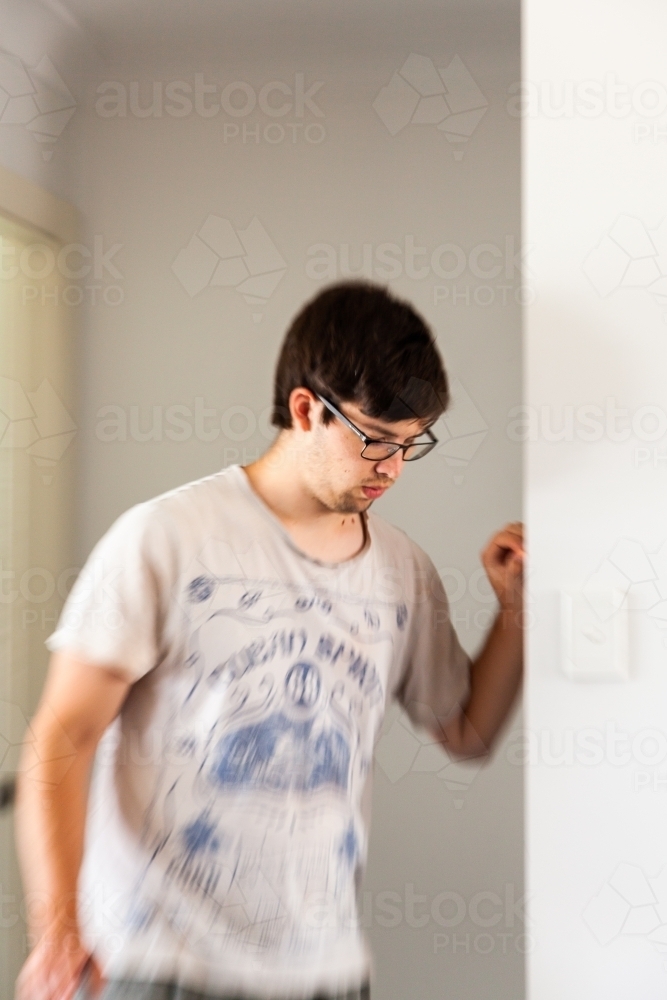 Person leaning on doorframe experiencing vertigo, spinning, dizziness - Australian Stock Image