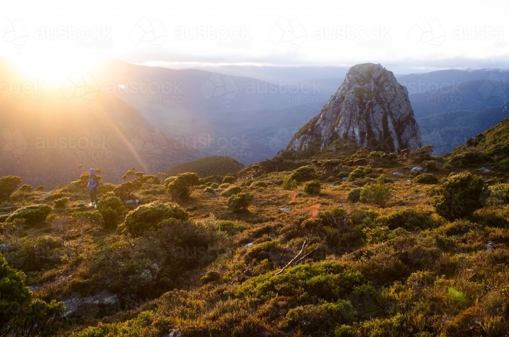 Person looking out at mountain range at sunset - Australian Stock Image