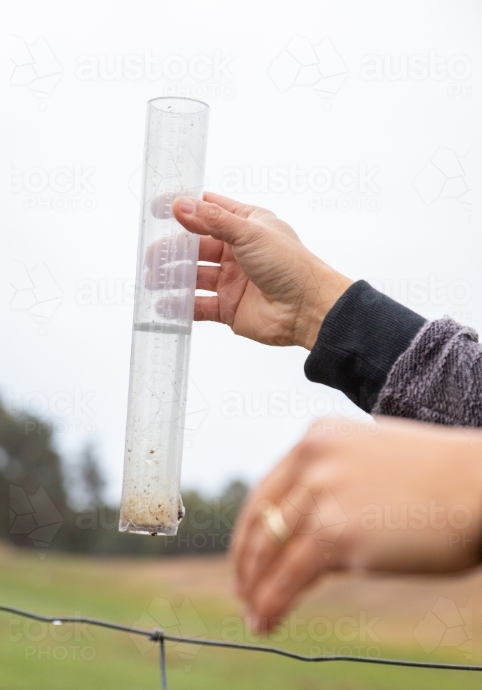 Person measuring rain in rain gauge - Australian Stock Image