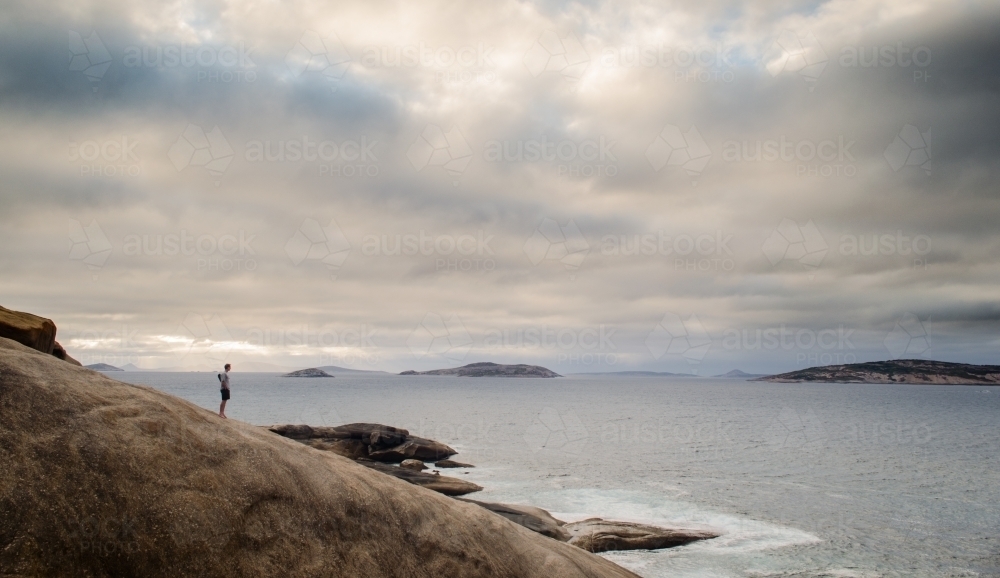 Person on rocks looking out over salmon beach - Australian Stock Image