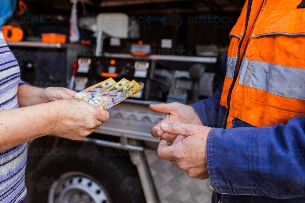 Person paying in cash for professional tradesman services - Australian Stock Image
