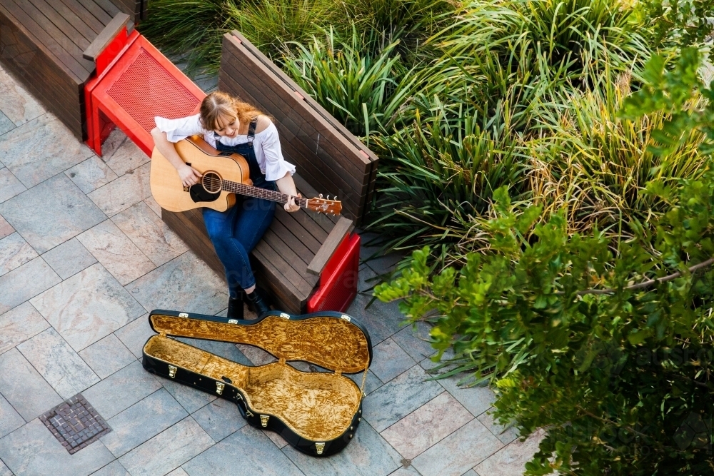 Person playing guitar on street footpath busking - Australian Stock Image