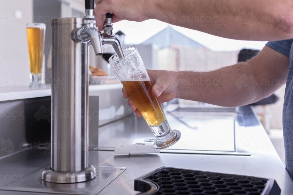 Person pouring beer from tap into a  glass - Australian Stock Image