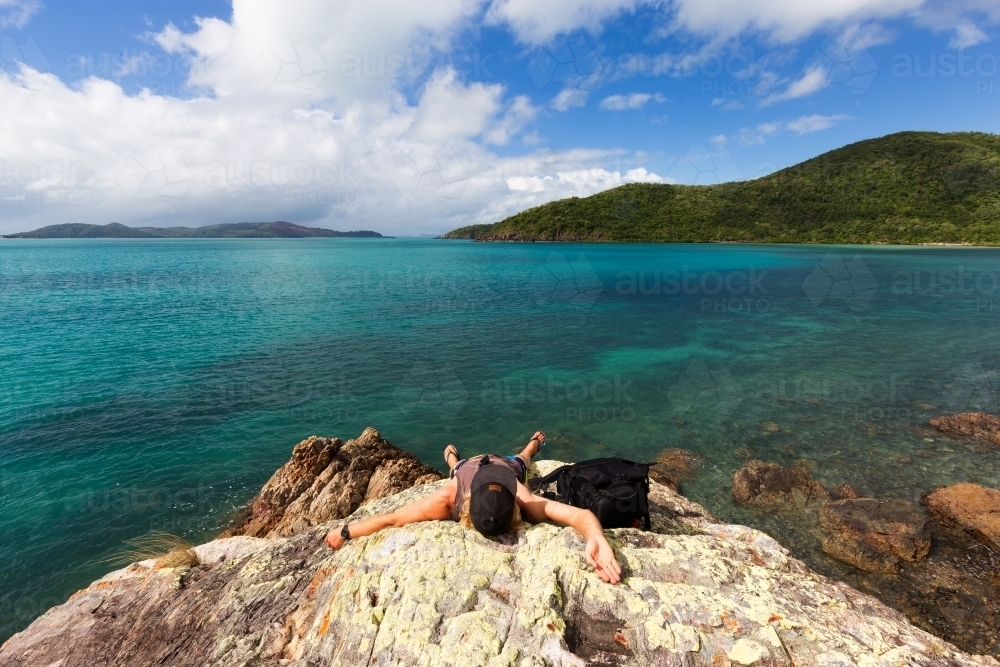 Person relaxing at a remote tropical, rocky beach in the Whitsundays - Australian Stock Image