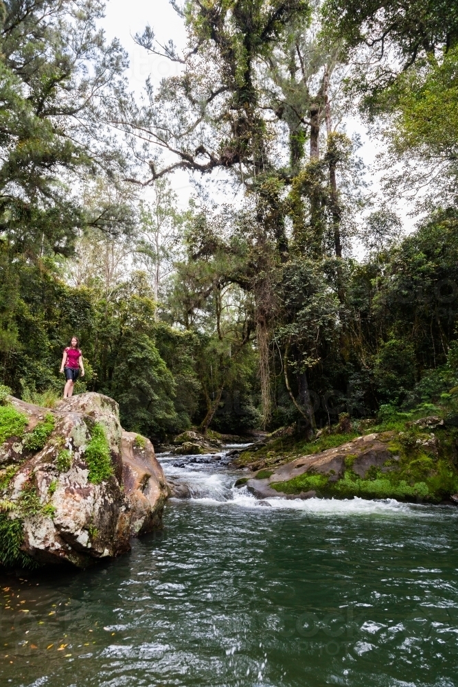 Person standing on boulder at the edge of pool at Ladies Well - Australian Stock Image