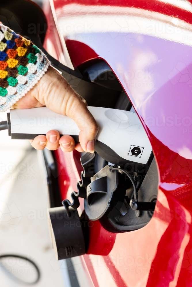 Person unplugging electric vehicle charging plug ready to travel - Australian Stock Image