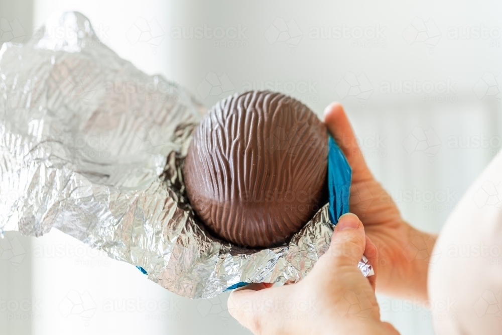 Person unwrapping chocolate easter egg - Australian Stock Image