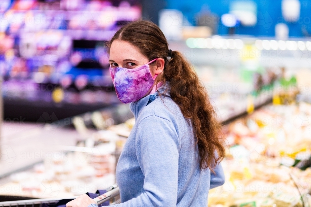 Image of person walking down grocery store aisle wearing home made face
