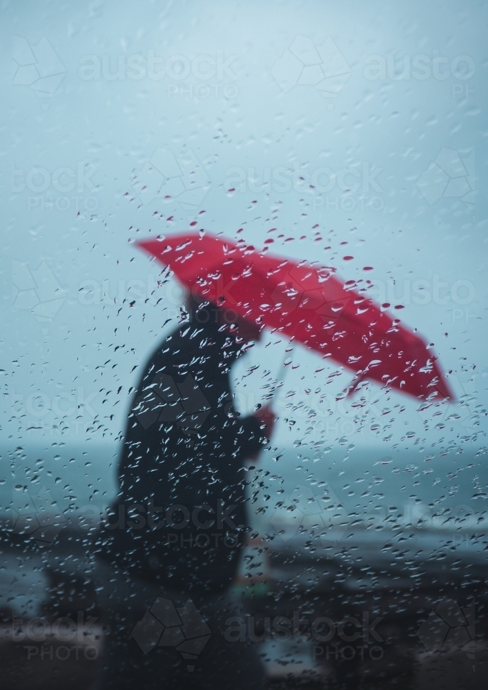 Person Walking with an Umbrella in the Rain - Australian Stock Image