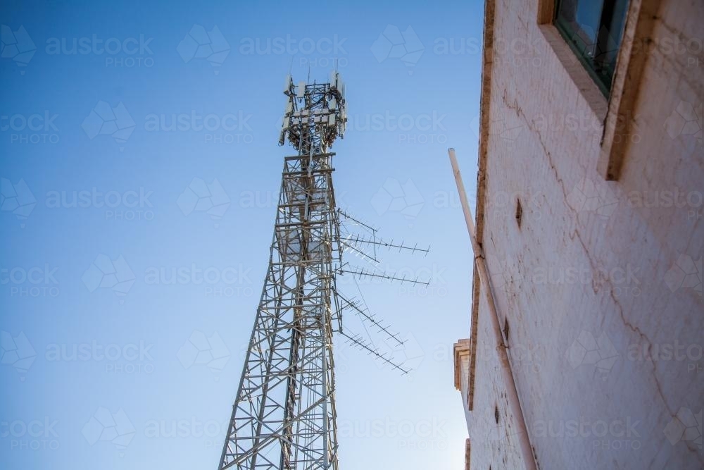Phone tower beside a brick building against blue sky - Australian Stock Image