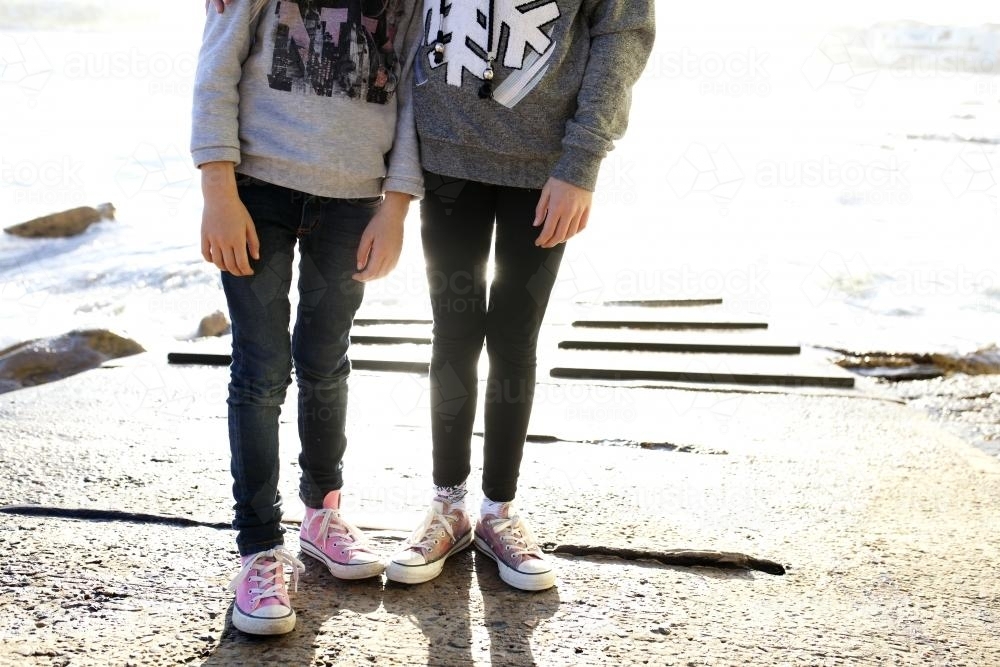Photo of girls legs standing on boat ramp by the ocean - Australian Stock Image