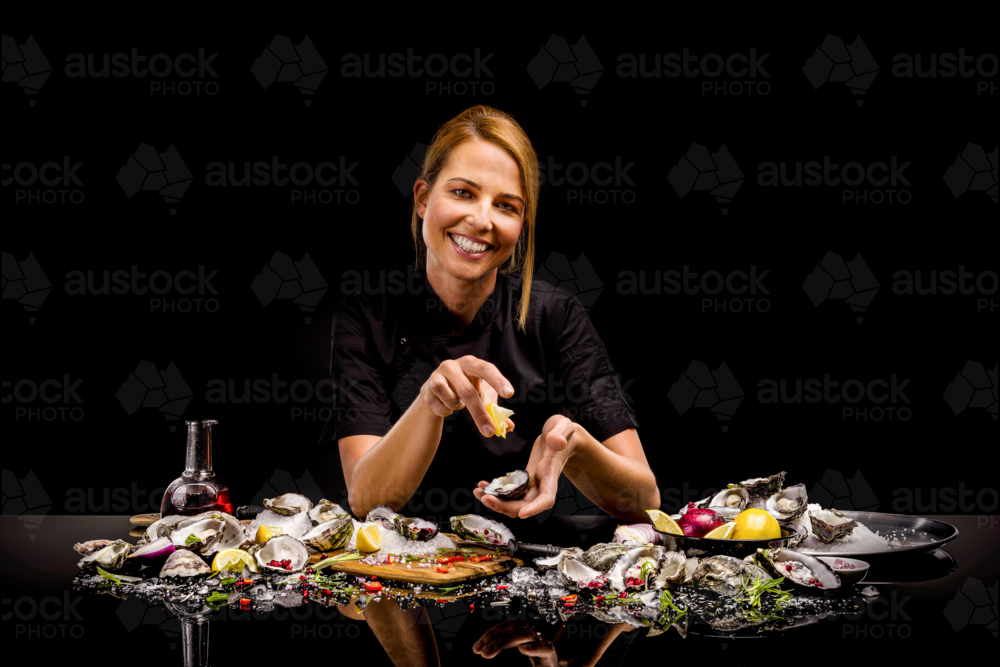 Photo of woman in chef uniform shucking oysters - Australian Stock Image