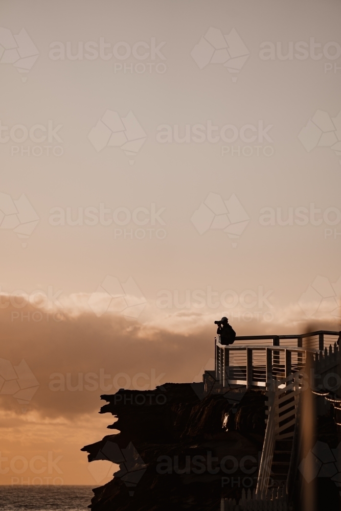 Photographer silhouette at the Bronte Beach headland at sunrise - Australian Stock Image