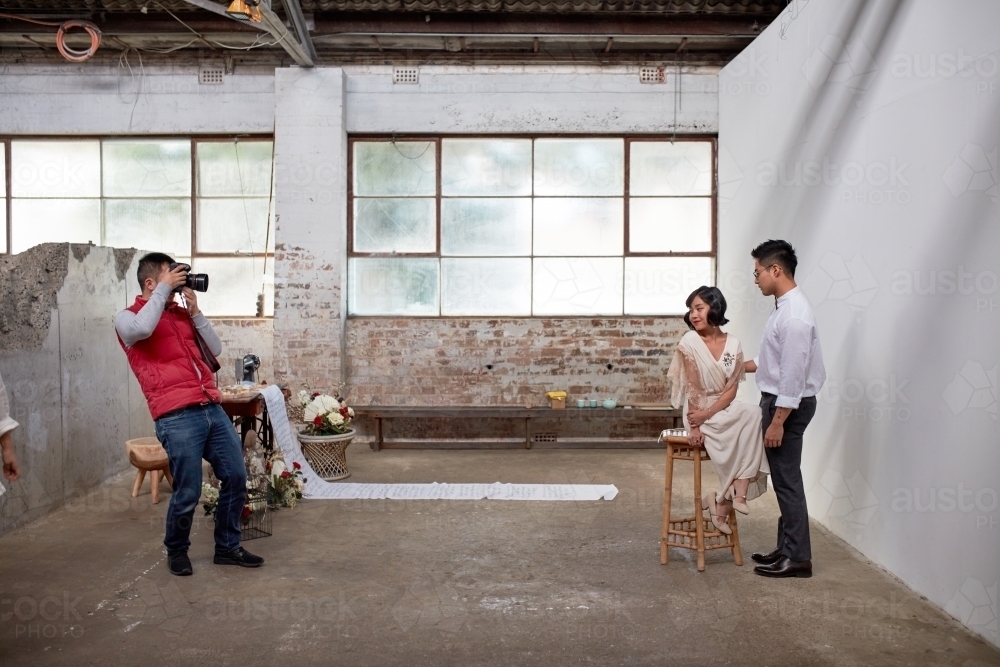 Photographer taking photos in warehouse of wedding couple - Australian Stock Image