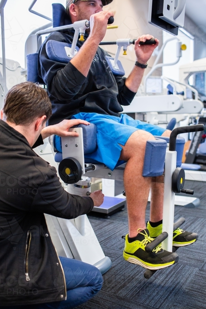 Physio adjusting exercise therapy equipment for client - Australian Stock Image