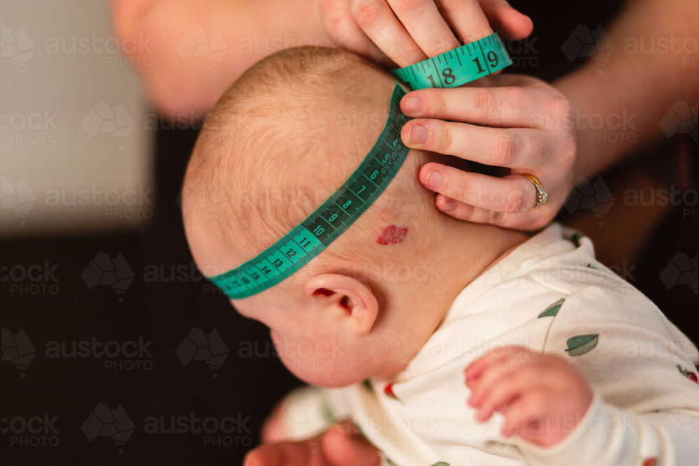 Physio performing Cranial Measurement assessment on baby - Australian Stock Image