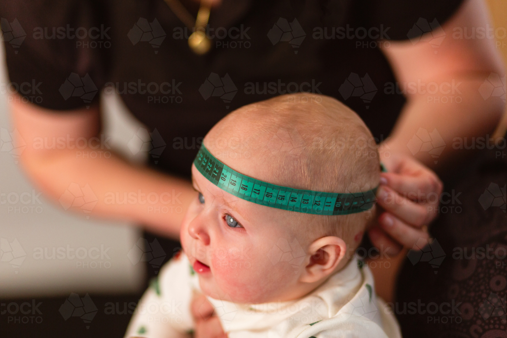 Physio performing Cranial Measurement assessment on baby - Australian Stock Image