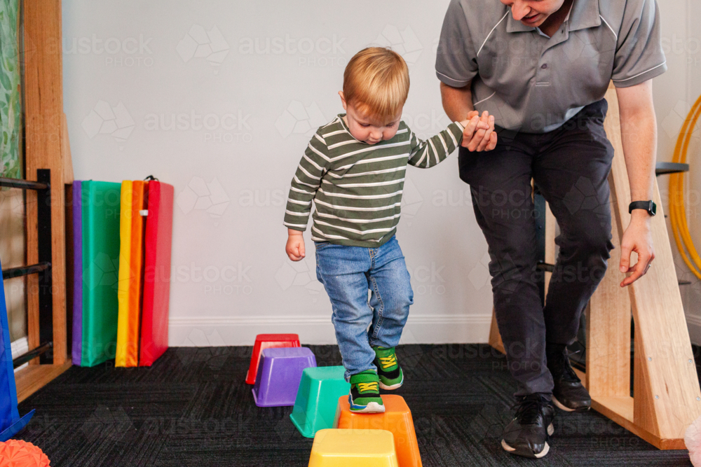 physio student working with young toddler boy on balance and coordination on stepping blocks - Australian Stock Image