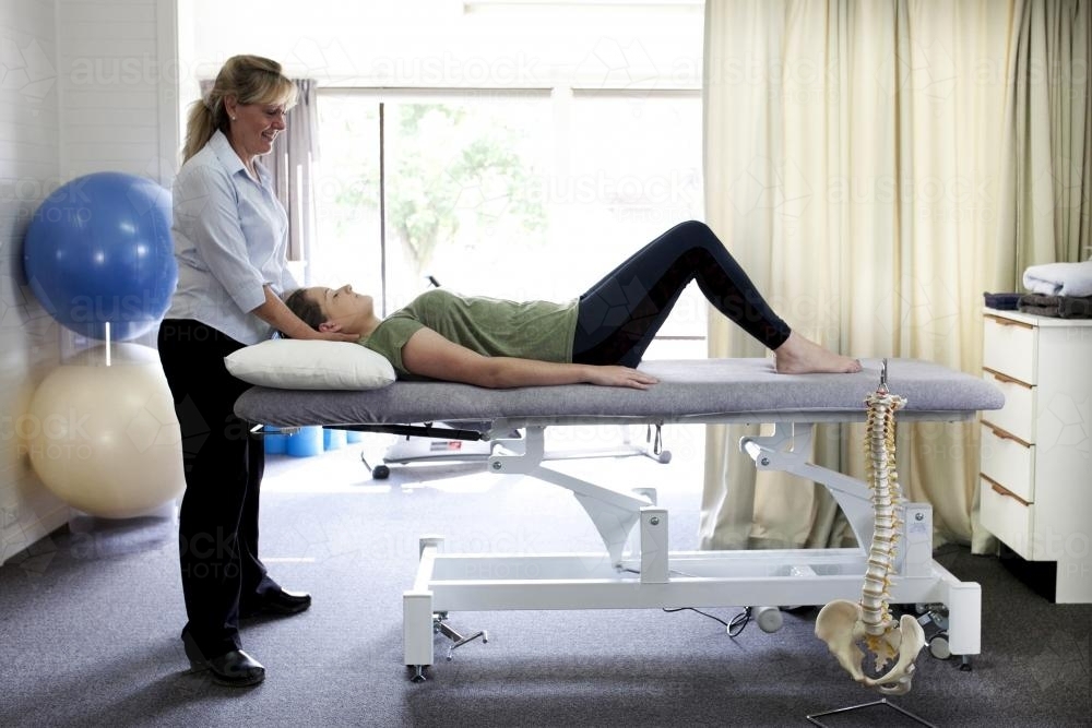 Physiotherapist treating a patient on a bed in a clinic - Australian Stock Image