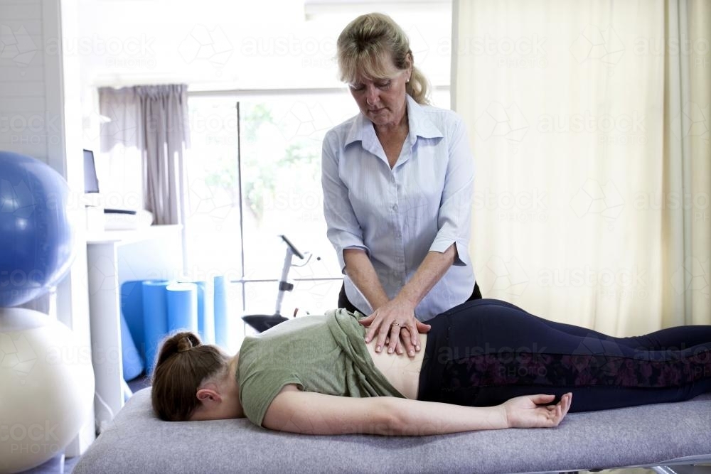 Physiotherapist treating female patient's back - Australian Stock Image