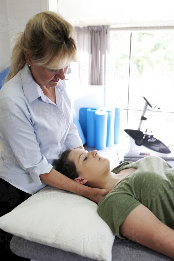 Physiotherapist treating female patient's neck - Australian Stock Image