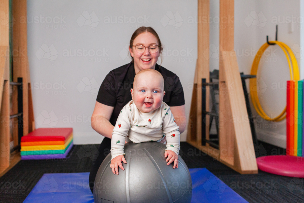 Vestibular Input Rocking Image of physiotherapist with baby on physio ball doing vestibular ...