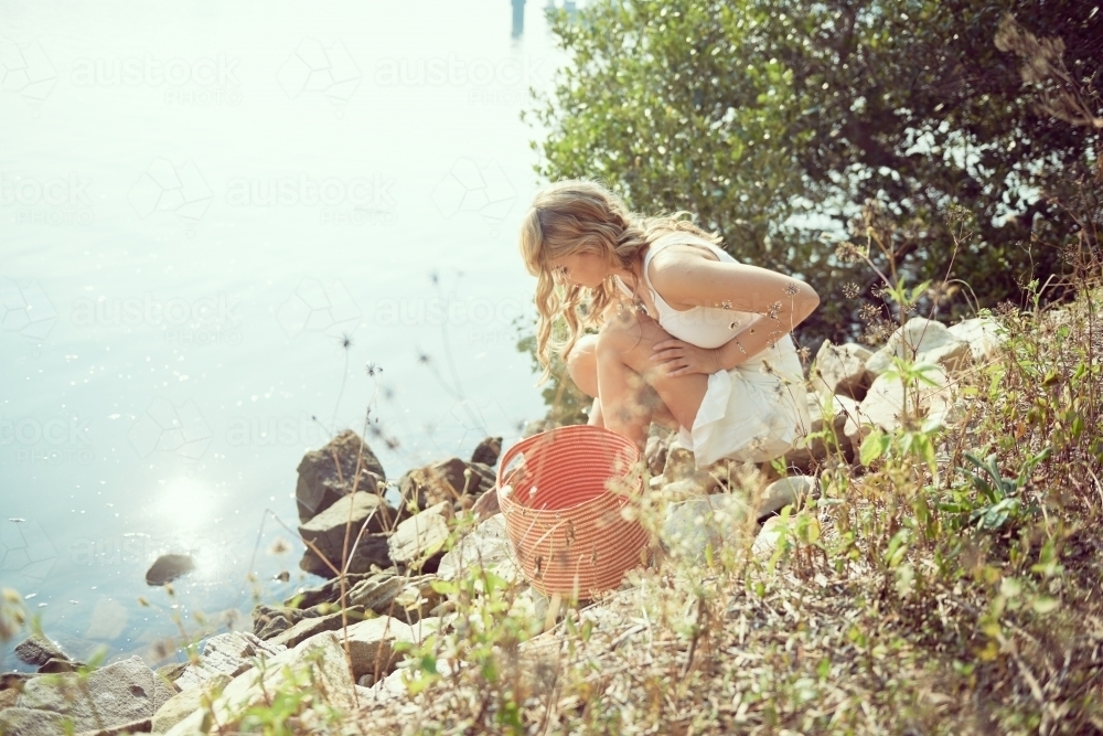 Picking flowers from stones by the water on a summer day - Australian Stock Image