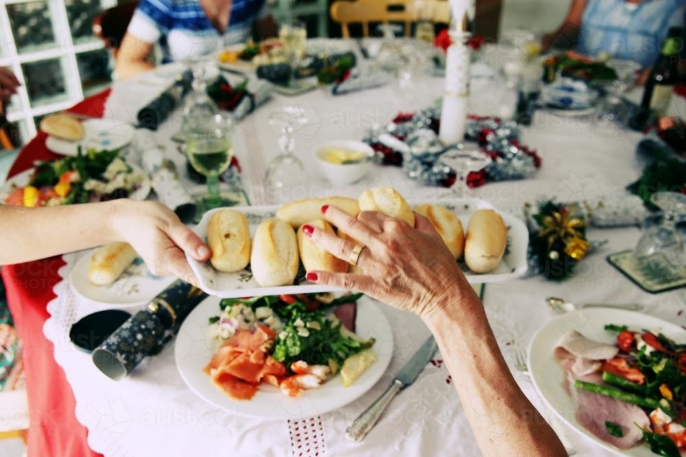 Picking up a bread roll at Christmas dinner - Australian Stock Image