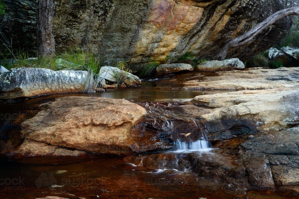 Picturesque creek with water tumbling over coloured sandstone - Australian Stock Image