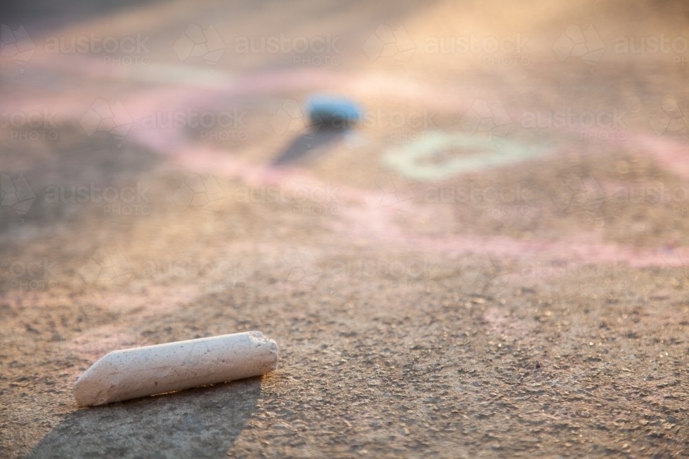 Piece of white coloured chalk left lying on concrete in afternoon light - Australian Stock Image