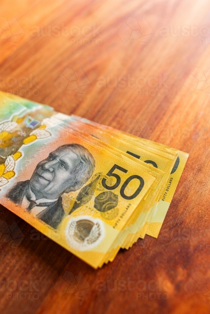 Pile of australian fifty dollar notes on wooden table top - Australian Stock Image