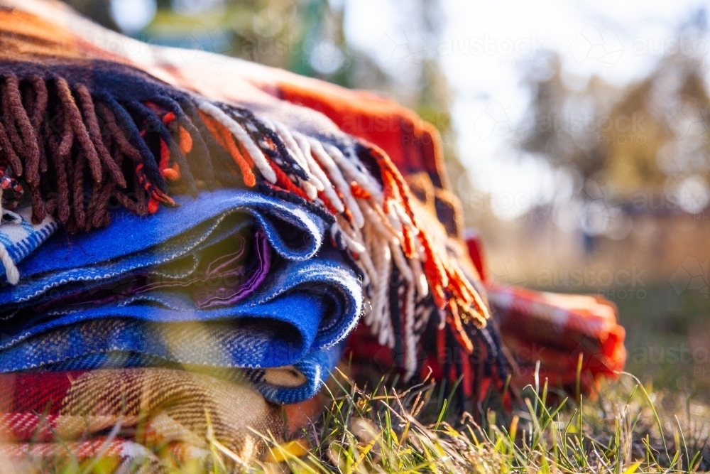 Pile of blankets on grass in winter for outdoor picnic - Australian Stock Image