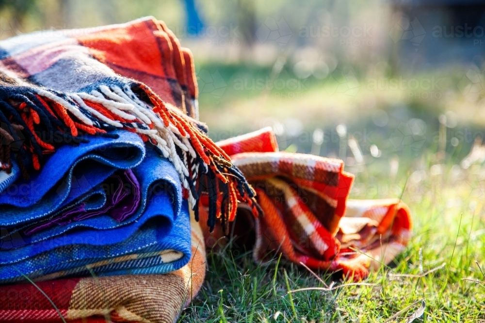 Pile of blankets on grass in winter for outdoor picnic - Australian Stock Image