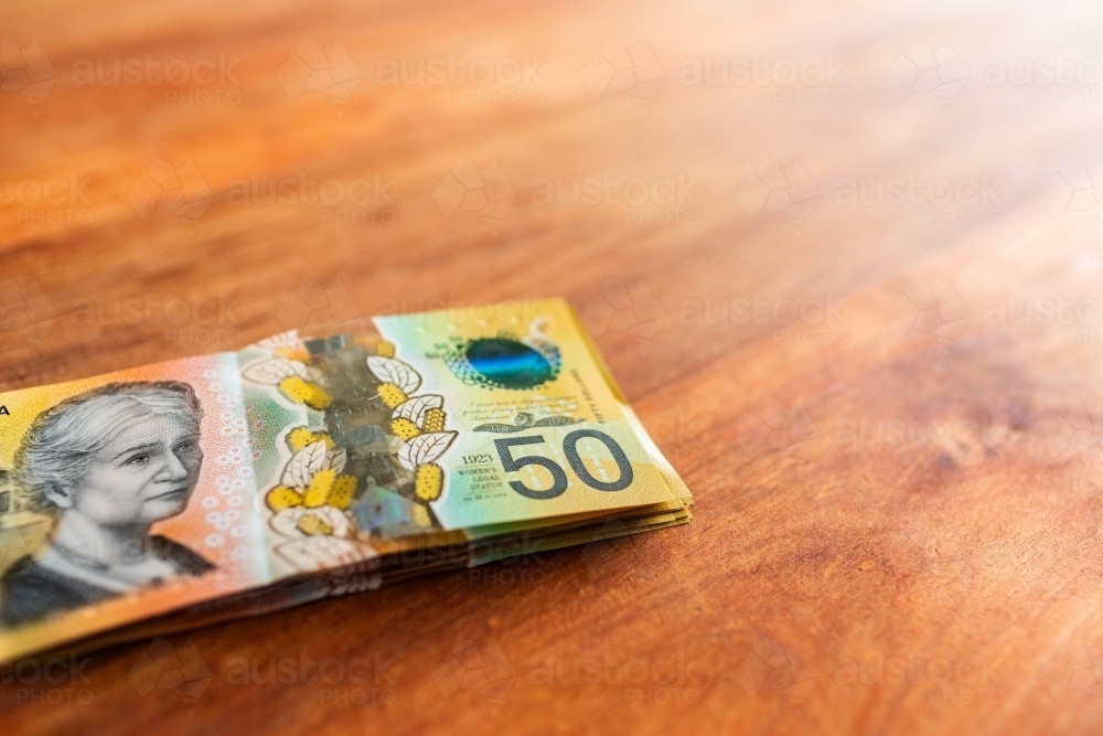 Pile of cash in fifties on wooden table with copy space - Australian Stock Image