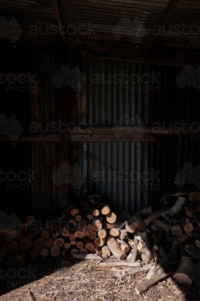 Pile of firewood in sunlit shed - Australian Stock Image