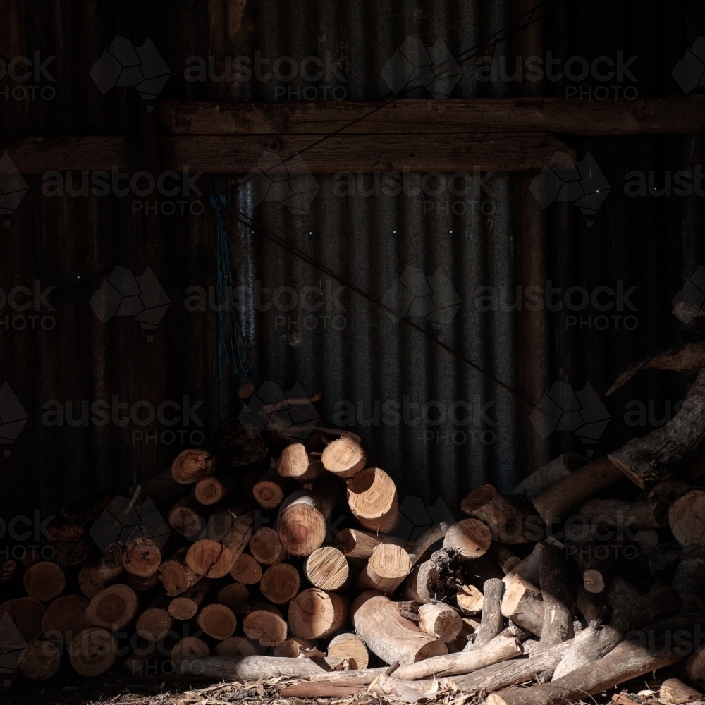 Pile of firewood in sunlit shed - Australian Stock Image