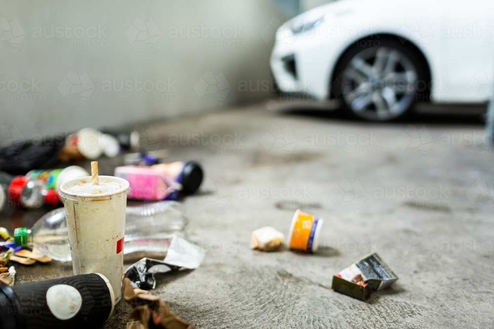 Pile of trash in corner of carpark, dirty takeaway cups and plastic bottle with cigarette packaging - Australian Stock Image