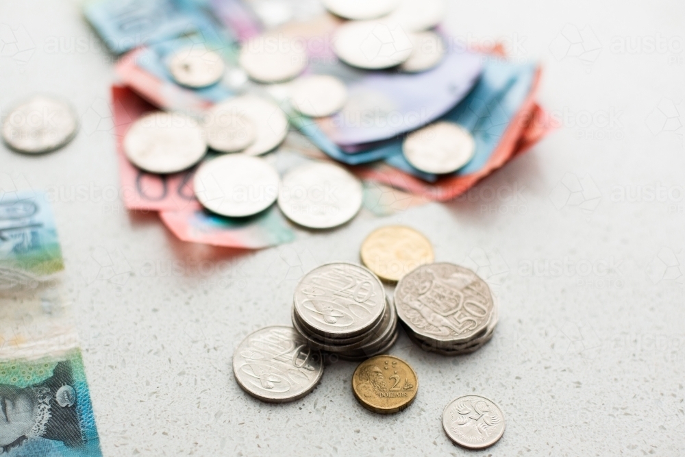 piles of Australian coins with other coins and notes in the background - Australian Stock Image