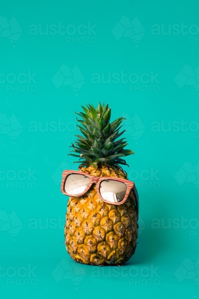 pineapple with sunglasses against a blue background - Australian Stock Image