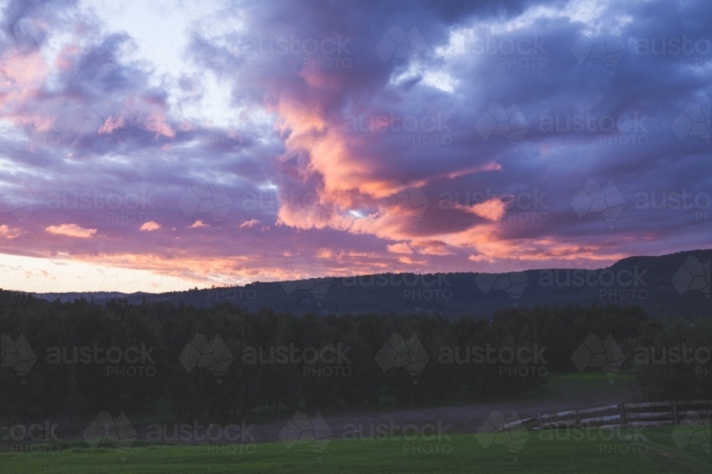 Pink and purple clouds over forest in rural Australia - Australian Stock Image