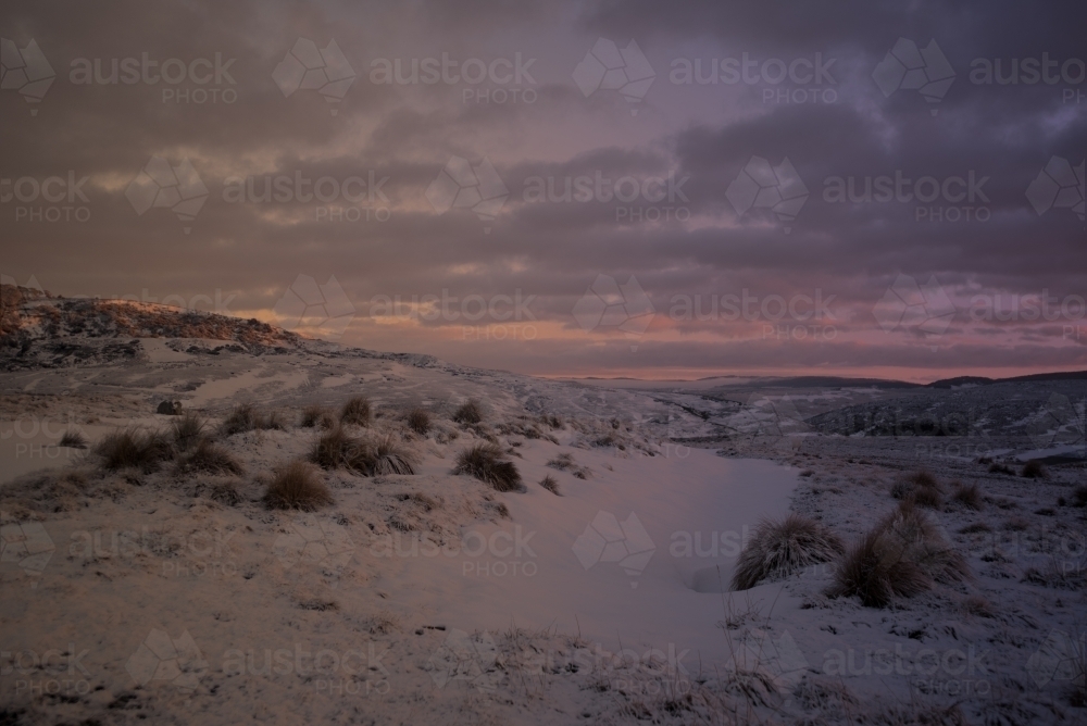 Pink sunrise over snow covered hills - Australian Stock Image