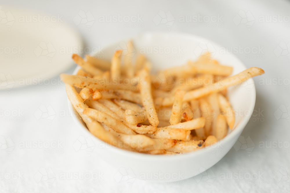 Plain white bowl of chips with minimalist background - Australian Stock Image