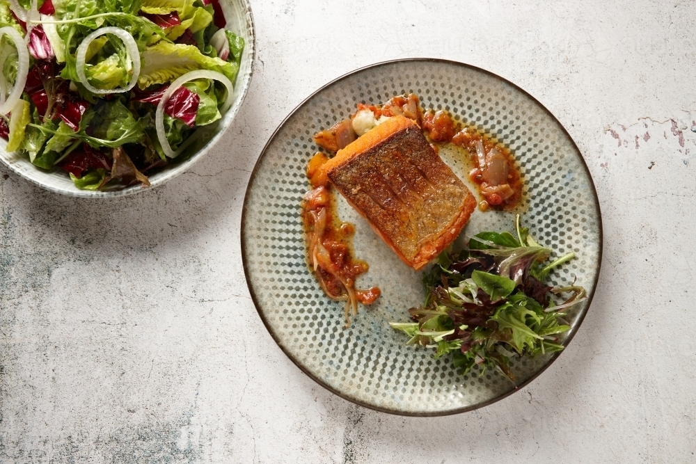 Plate of fish with bowl of salad on the side - Australian Stock Image